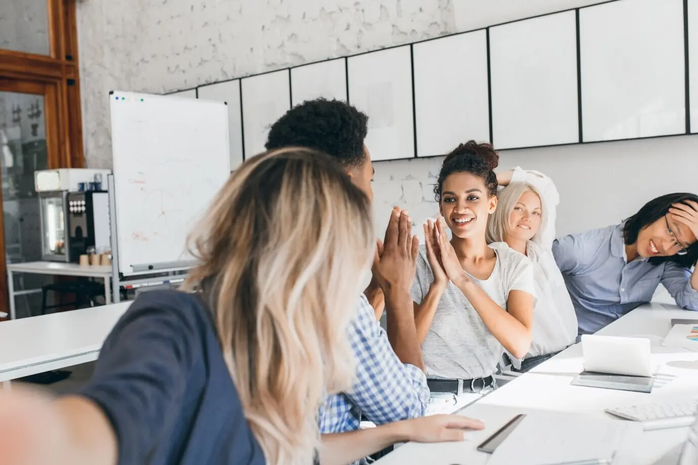 Африканка в футболке играет с коллегой в забавную игру в офисе. Привлекательная молодая сотрудница дурачится с чернокожим мужчиной во время встречи в конференц-зале.