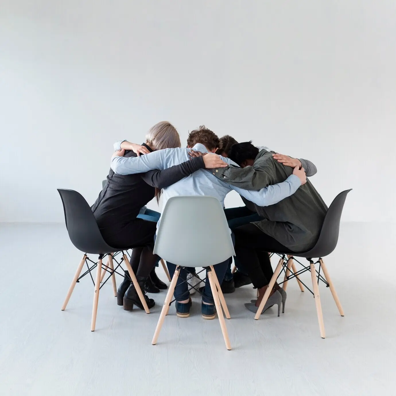 Пациенты на реабилитации стоят на стульях и обнимаются.